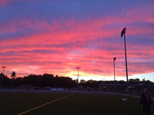 THE VIBRANT HUES of a glorious pink sunset illuminate the newly installed athletic field lights that rise above the treetops at the high school’s new turf field facilities. (Courtesy Photo)