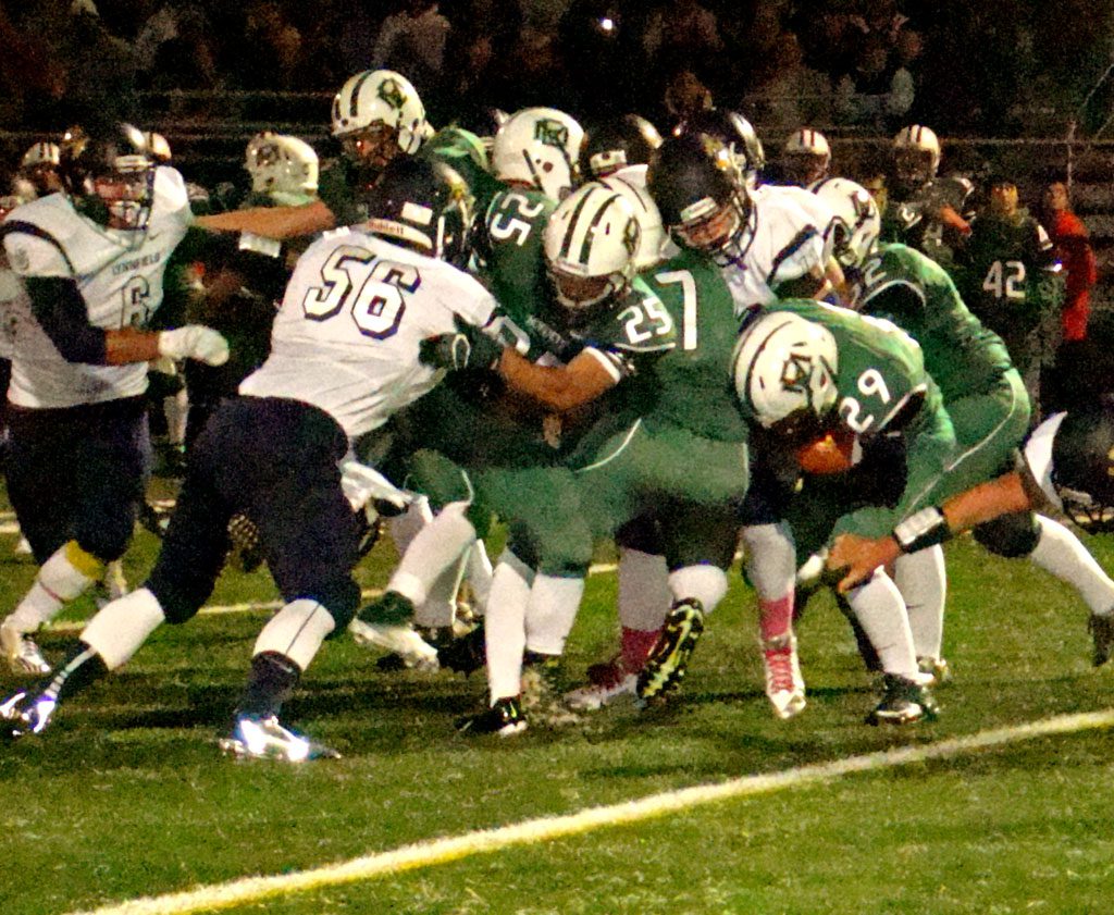 PIONEER captain David Adams (56) and Jake Rourke (6) fight to take down Hornet ballcarrier Chris Carr (29) in first period action of Lynnfield's 42-7 win. (Tom Condardo Photo)