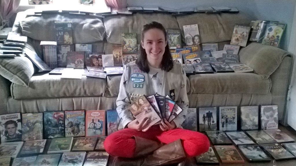 MOVIES FOR A CAUSE. Girl Scout Emily Precourt, 18, poses with the avalanche of 115 DVDs geared for tweens and teens that she collected and donated to Boston Children's Hospital. The project earned her the Gold Award, the highest award in Girl Scouting. (Courtesy Photo)
