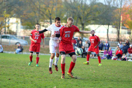 ANDREW AULD, a junior (#25), fends off a Melrose player during a recent game which Wakefield won, 5-2. In the back are Neil Fitzgerald (#10) and Mo Jenga (#18). The Warriors also posted a 5-2 triumph yesterday afternoon against Swampscott in the regular season finale at Swampscott High School. (Donna Larsson File Photo)