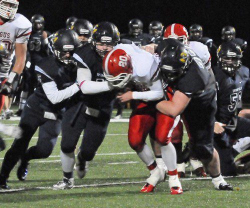 FAMILIAR SIGHT. Tenacious Pioneer defenders (l-r) Alex Soden (5), C. J. Finn (11), and Steven White (77) collapse on Sachem runner Dan Cacciola Saturday. (Jack Schnelle Photo)