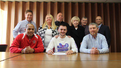 SENIOR JACKSON Gallagher (front row, center) signed his commitment letter to attend UMass Lowell on a track and field scholarship. The River Hawks are a Div.1 program. Gallagher was the 2014 Div 4. state champion in the 600 meter run during the indoor track season and WMHS school record holder in that event. In the front row (from left to right) are WMHS boys’ indoor and outdoor track head coach Ruben Reinoso, Gallagher, and boys’ cross country head coach and assistant track coach Perry Pappas. In the back row (from left to right) are Director of Athletic and Student Activities Mike Boyages, Gallagher’s parents, Colleen Gallagher and Bill Boc, Jackson Gallagher’s grandparents, Kathleen Gallagher and Robert Gallagher and WMHS Principal Richard Metropolis. 