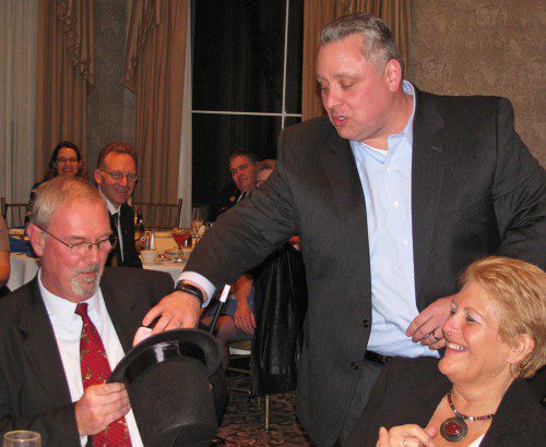 FINANCE COMMITTEE Chairman Jack Dahlstedt presents retired Town Administrator Bill Gustus (l) with a magician's hat and magic wand in honor of his financial wizardry on behalf of the town at his retirement party Friday. At right is Gustus's wife, Laura. (Mark Sardella Photo)