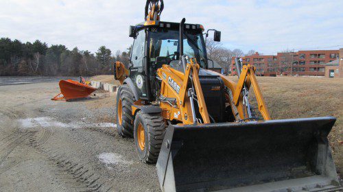DON’T WORRY. It’s coming. The plow in back of the front end loader parked near the Department of Public Works pumping station on Broadway has been lying mostly idle this winter, but over the weekend Mother Nature is expected to deliver three to six inches of snow to the region. (Gail Lowe Photo)