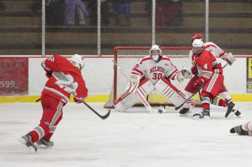 DOM BRUNO, a senior defenseman (#22), fired a shot on Melrose goalie Tyler Brown (#30) as senior forward Joe Stackhouse (#4) gains position in front of the net. The Warriors played a good game but fell short against the Red Raiders by a 3-2 score last night at the Kasabuski Arena. (Donna Larsson Photo)