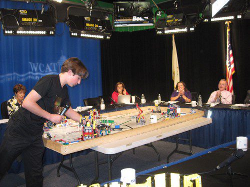 AT last night’s school board meeting, Wakefield student Cole Kraus demonstrated how a robot designed by him and other robotics team members could solve a puzzle in two-and-a-half minutes. Kraus and Galvin Middle School students Sydney Yee and Calvin Yee and high school student Preston Yee will attend a FIRST Robotics Competition in St. Louis next week after having won the statewide robotics competition. All robotic moves are through visual programming, explained Lester Yee, coach for the team. (Gail Lowe Photo)