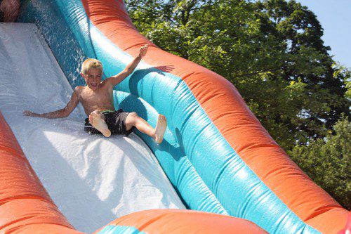 WET AND WILD. Recreation Station camper Camden Marengi laughs on his way down the slippery waterslide while being sprayed with cold water on a hot morning last Friday. (Maureen Doherty Photo)