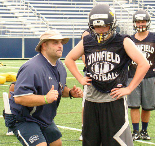 LINE COACH Gino Fodera demonstrates proper technique to sophomore Kenny Babine during the first conditioning practice of the season Monday. (Tom Condardo Photo)
