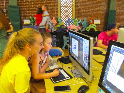 WAKEFIELD MEMORIAL HIGH SCHOOL student Mary Tannian showed Lily Sullivan, grade 1 student at the Greenwood School, how to create graphic art on a computer during Visual Arts Night, Tuesday, April 11. Lily is the daughter of Kelly and Brian Sullivan of Greenwood. (Gail Lowe Photo)